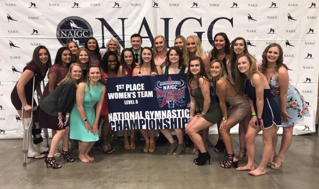 Gymnastics athletes pose with national championship banner at year-end banquet.